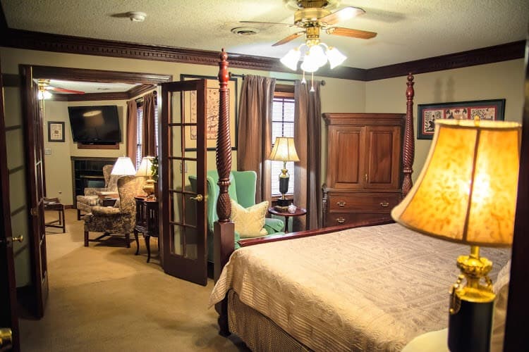 A cozy bedroom with a wooden bed, plush seating area, and decorative furnishings.