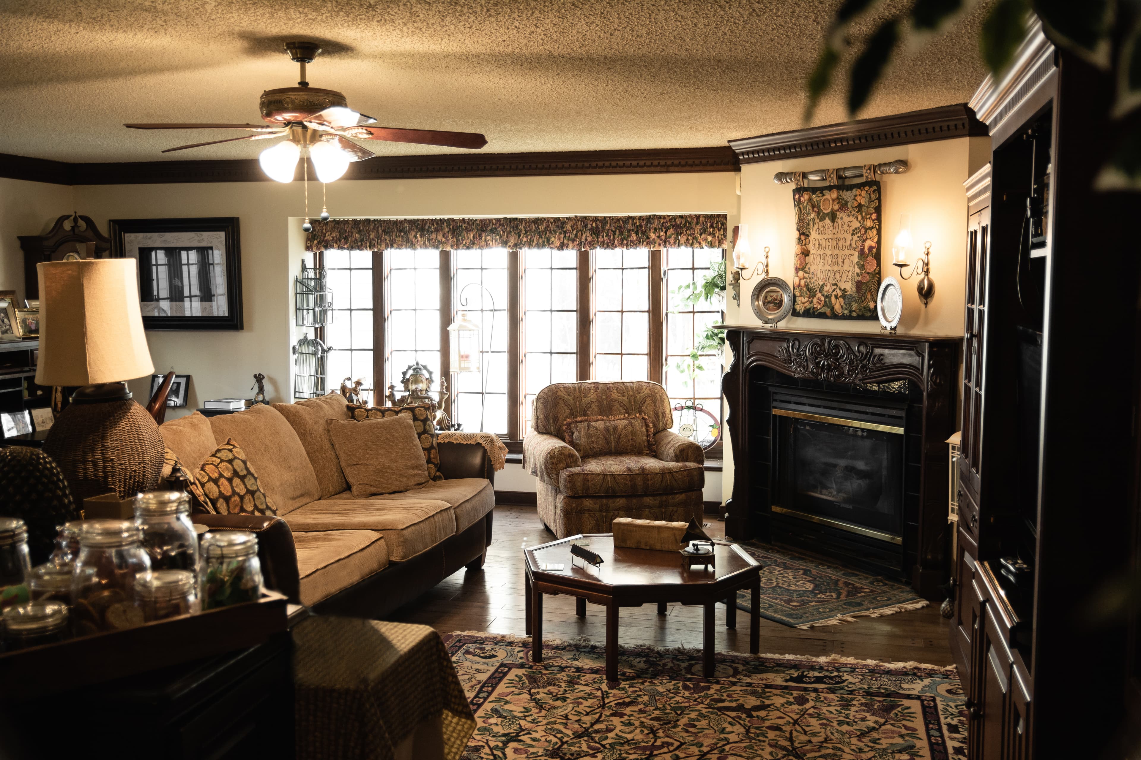 Cozy living room with a sofa, armchair, coffee table, fireplace, and large windows.