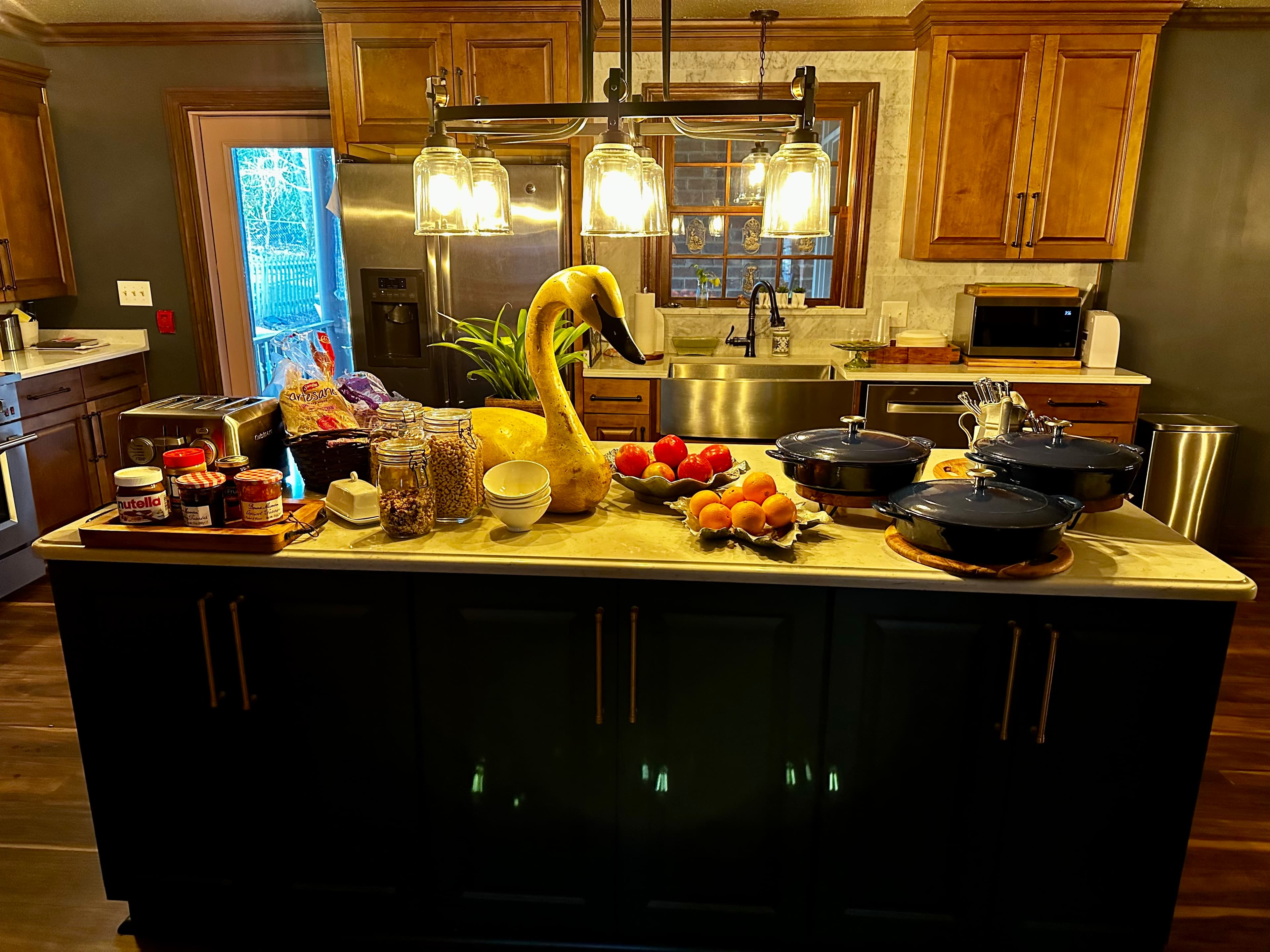 A beautifully arranged kitchen island featuring various foods, cookware, and a decorative swan.