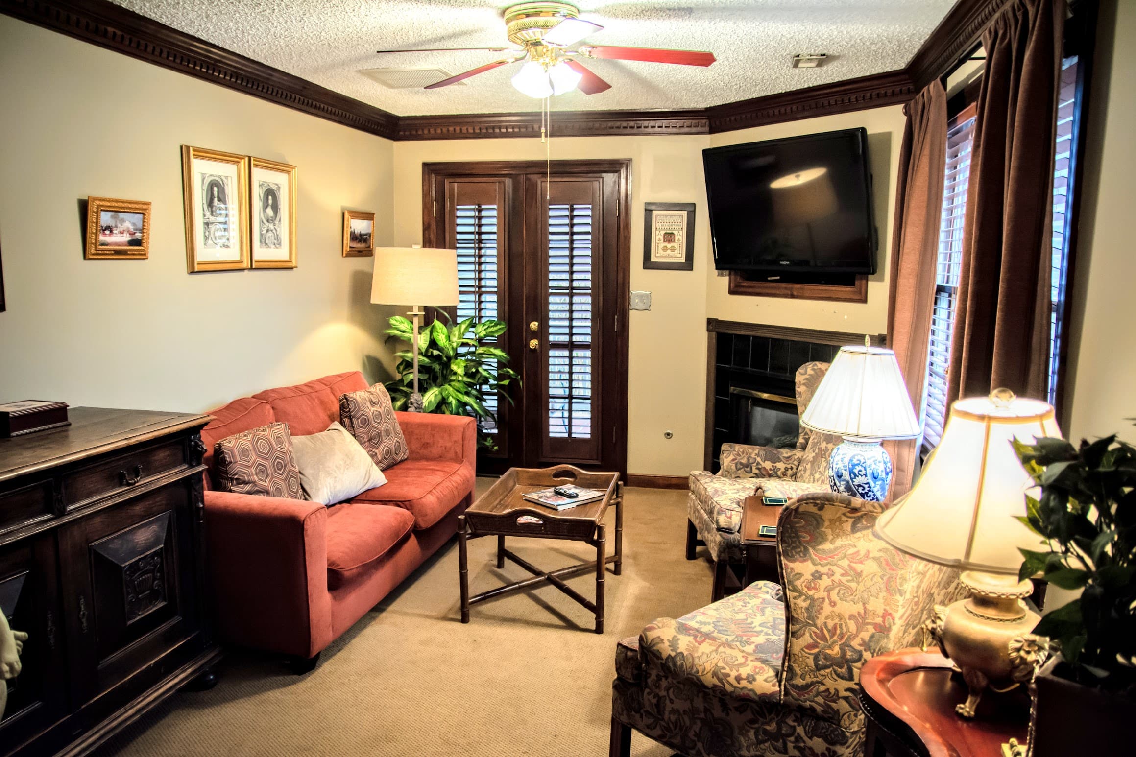 Cozy living room featuring a red sofa, armchairs, a coffee table, and a mounted TV.